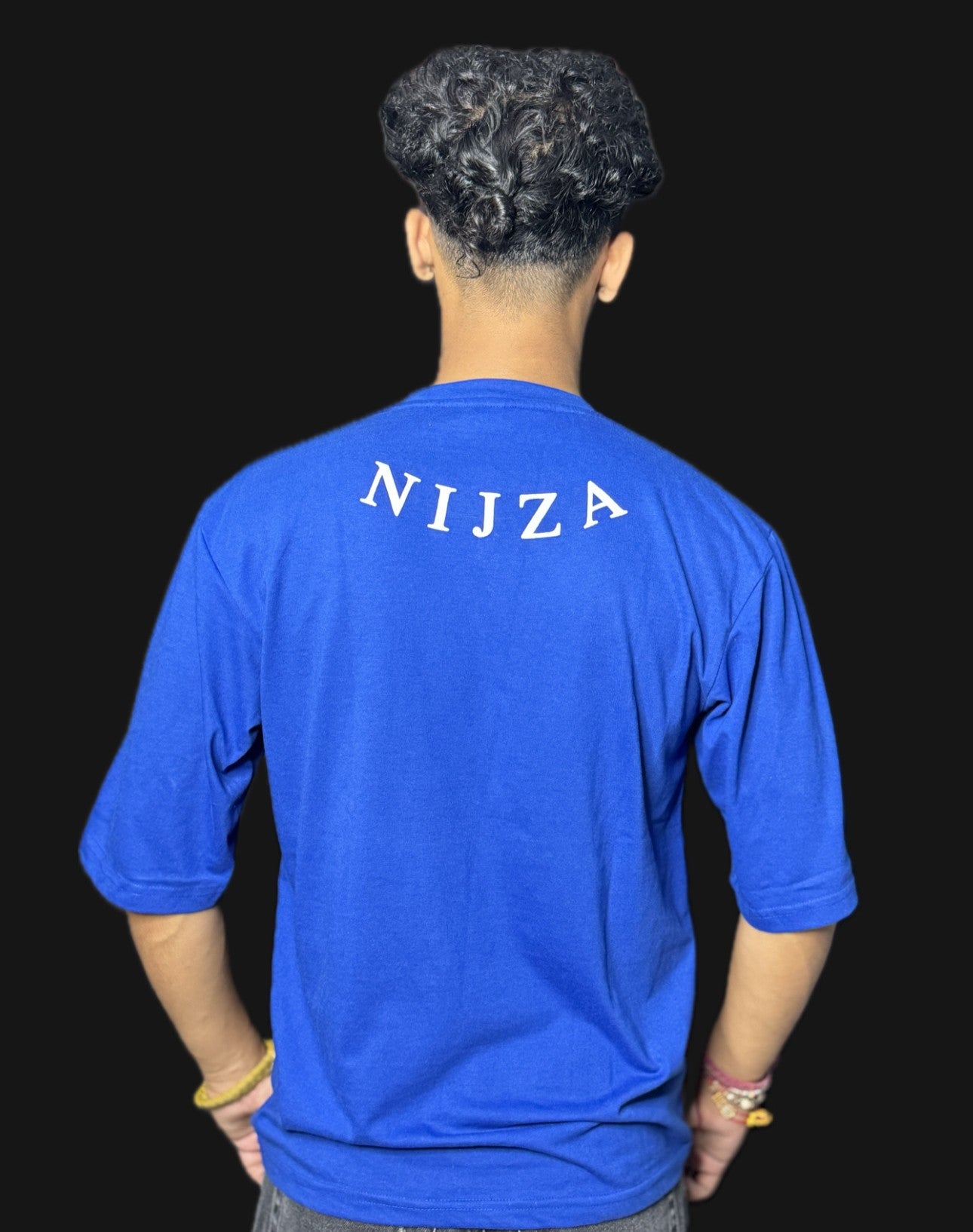 Person wearing a blue shirt with 'NIJZA' printed on the back against a black background