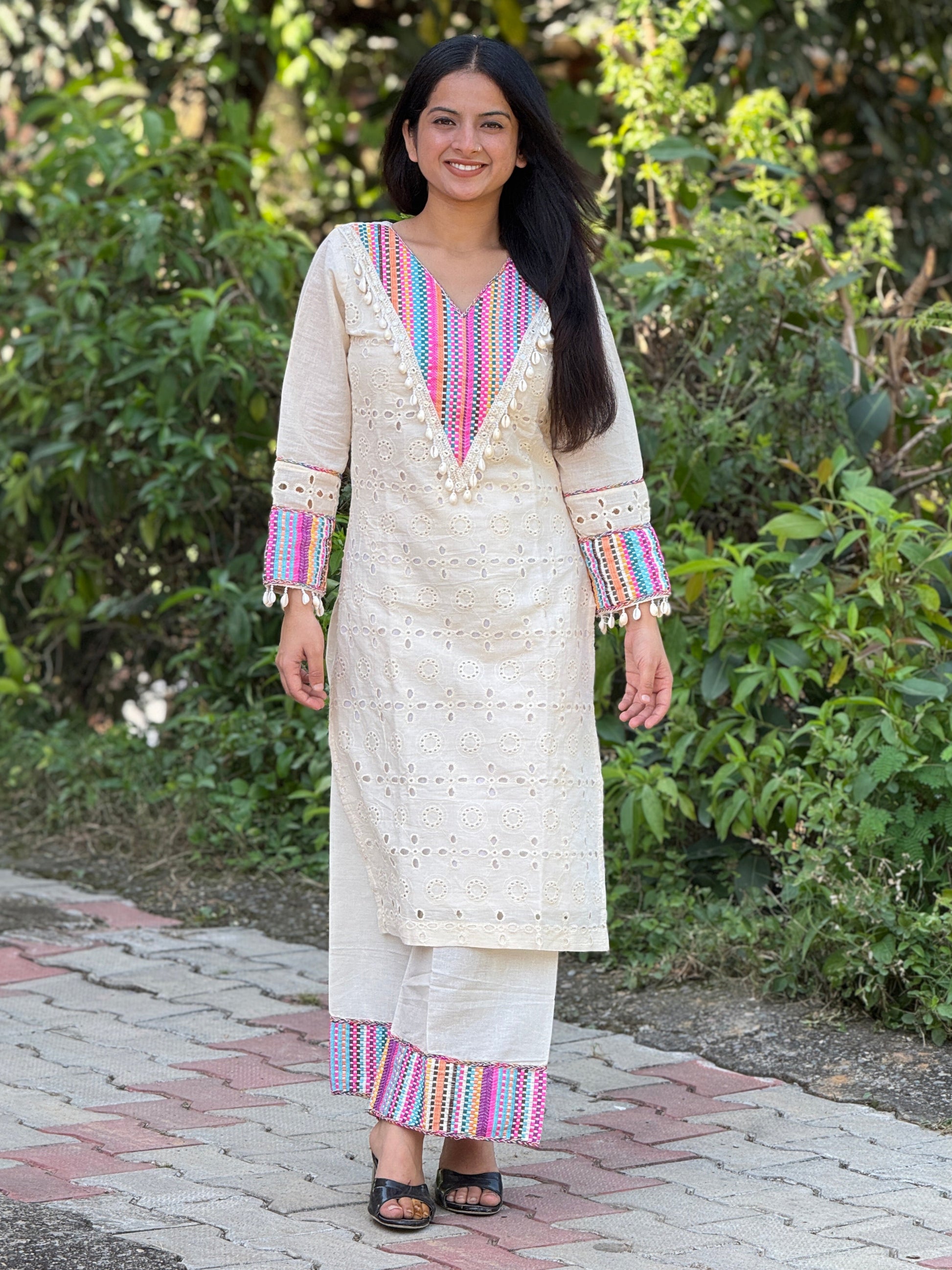 Woman wearing a traditional outfit with colorful patterns standing outdoors.