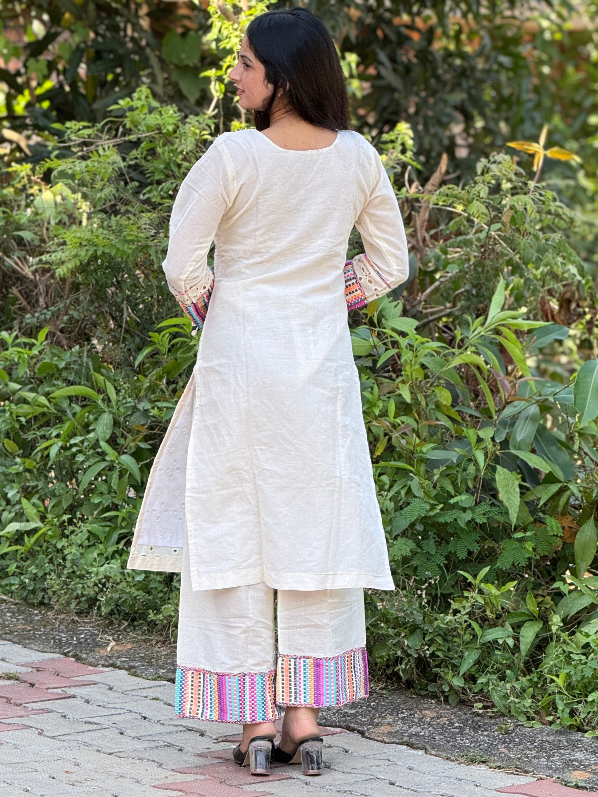 Woman in a white traditional outfit standing in a garden