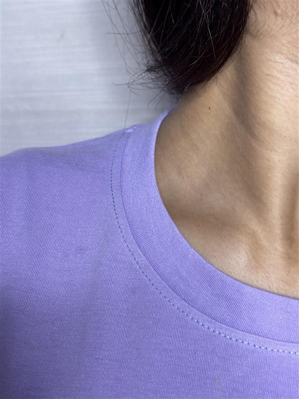 Close-up of a person wearing a purple shirt with a neutral background