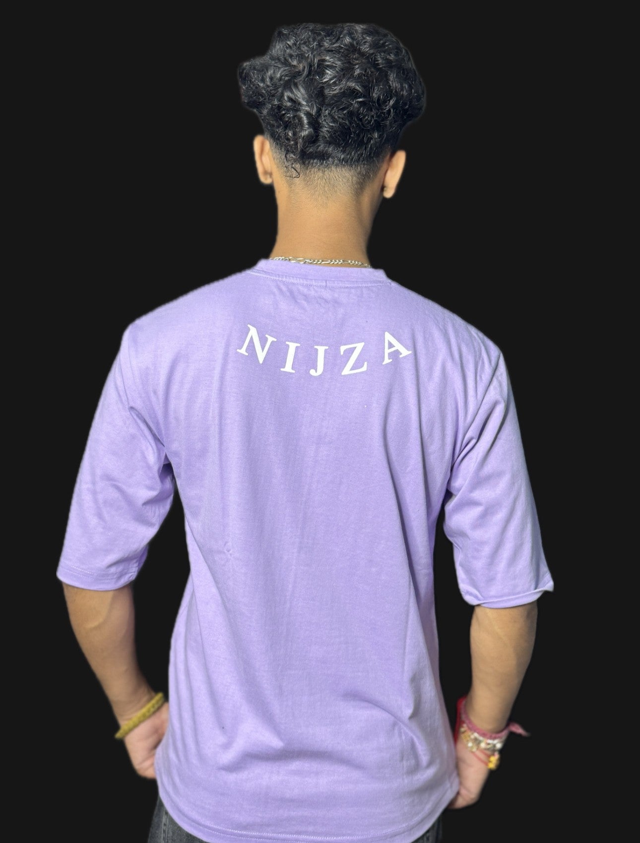 Person wearing a purple t-shirt with 'Nijza' printed on the back against a black background
