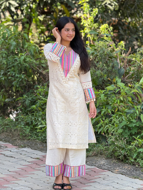 Woman wearing a traditional outfit with colorful patterns standing outdoors.