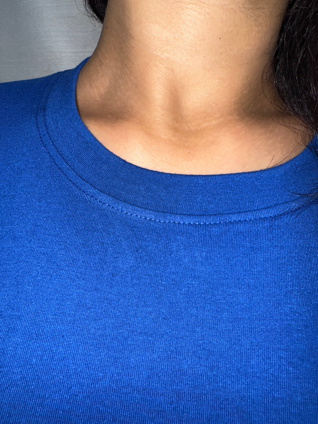 Close-up of a person wearing a blue tank top with a neutral background