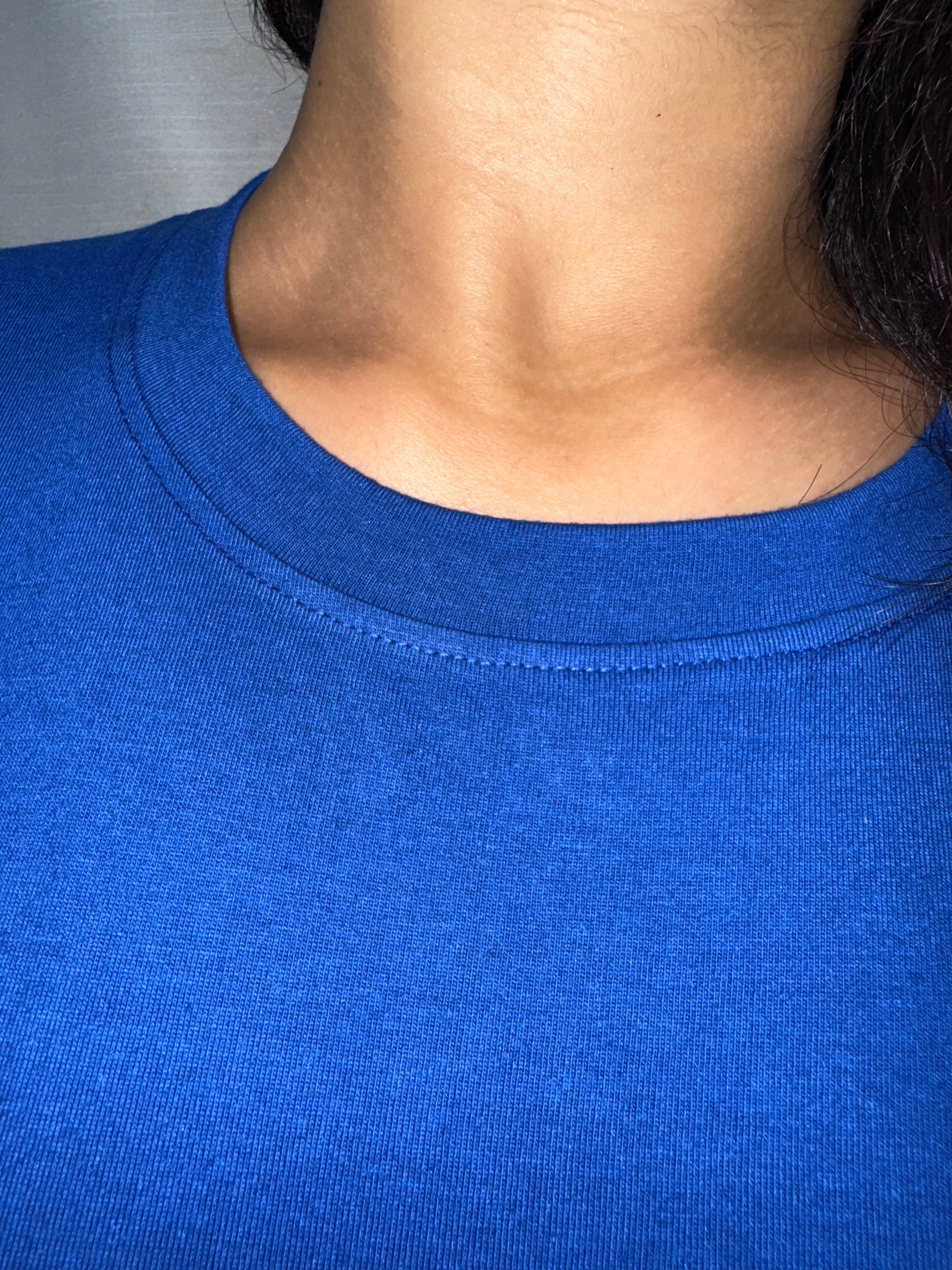 Close-up of a person wearing a blue tank top with a neutral background